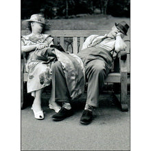  Front of card that shows a couple dressed in evening clothes, asleep on a bench. 