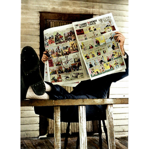 Man reading the funnies in the newspaper with his legs up