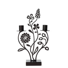  An enchanting candle holder crafted from sleek black iron, resembling a charming flower meadow. Featuring two taper candle holders atop a sturdy iron platform, adorned with four intricately detailed flowers and delicate leaves, evoking a sense of whimsical elegance.