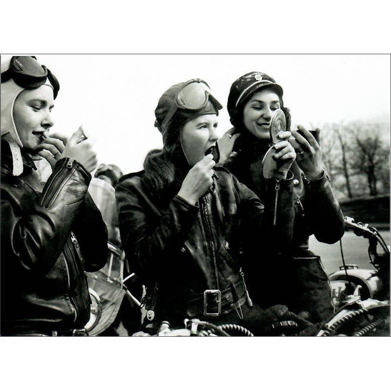  The front of the card shows three glamorous biker girls all applying lipstick and the picture was taken in the 1950s.