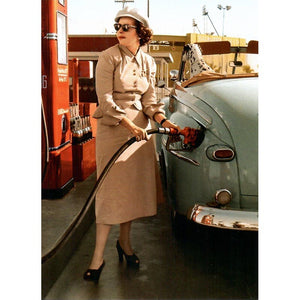The front of the card shows the word pumping gas wearing a dress a hat a pair of heels and a pair of sunglasses. The car is a convertible with a Dalmatian sitting inside and it is light to medium green. 